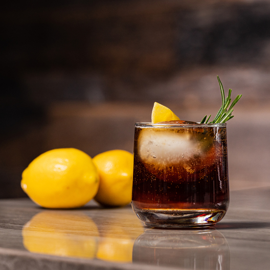 Supercharged Cold Brew and Tonic in a glass next to 2 lemons